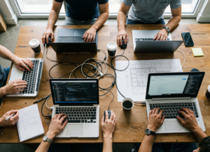 Several coworkers on their laptops working together at a table; photo is taken from above