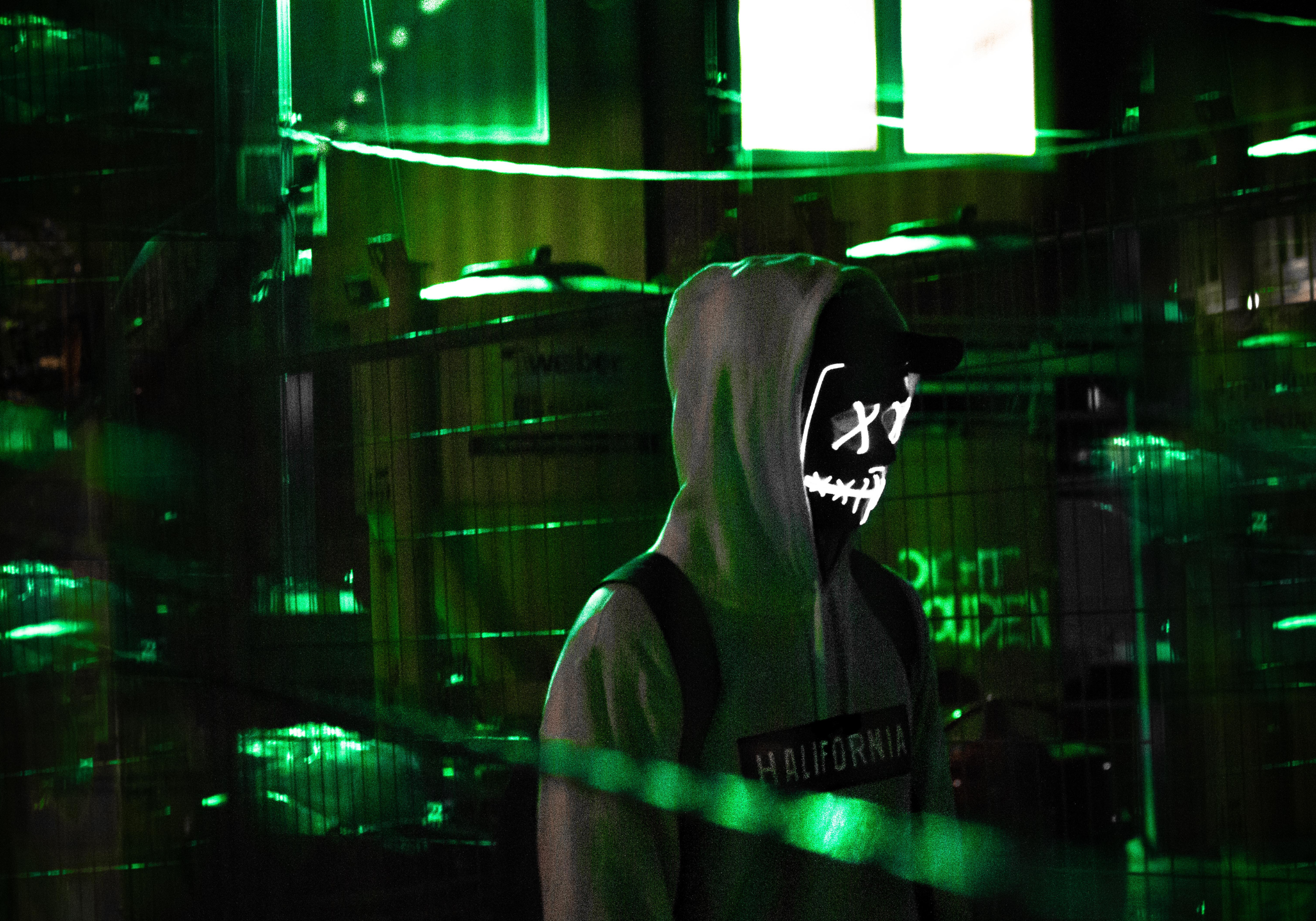 cyber criminal in a darkly lit room surrounded by computers